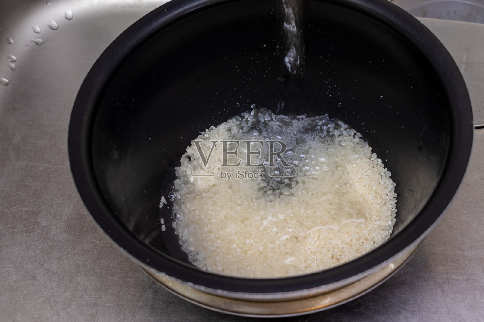 在一个黑色的碗里用水洗米粒照片摄影图片