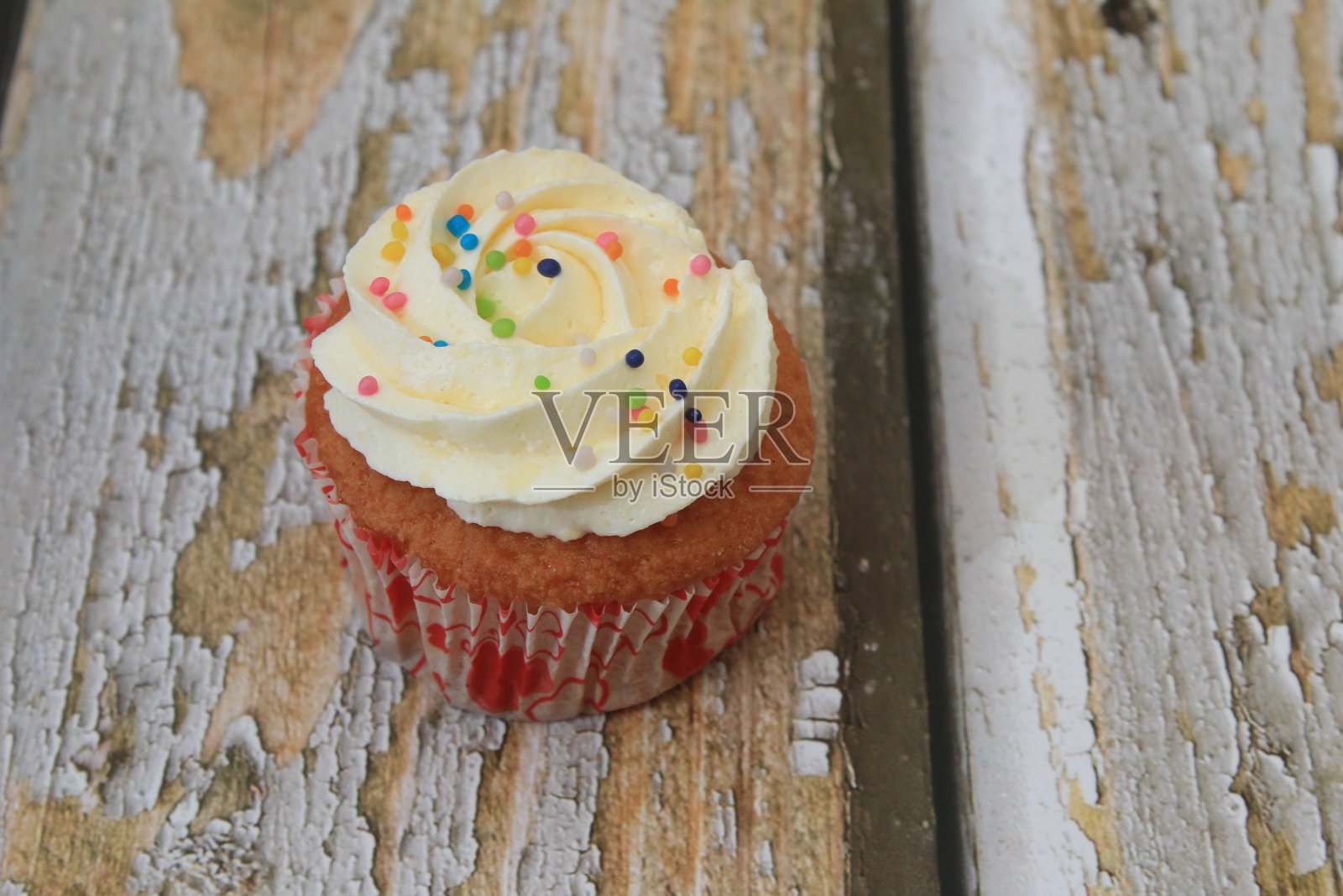 甜蛋糕与tutti frutti洒在木制桌子上白色的背景。照片摄影图片