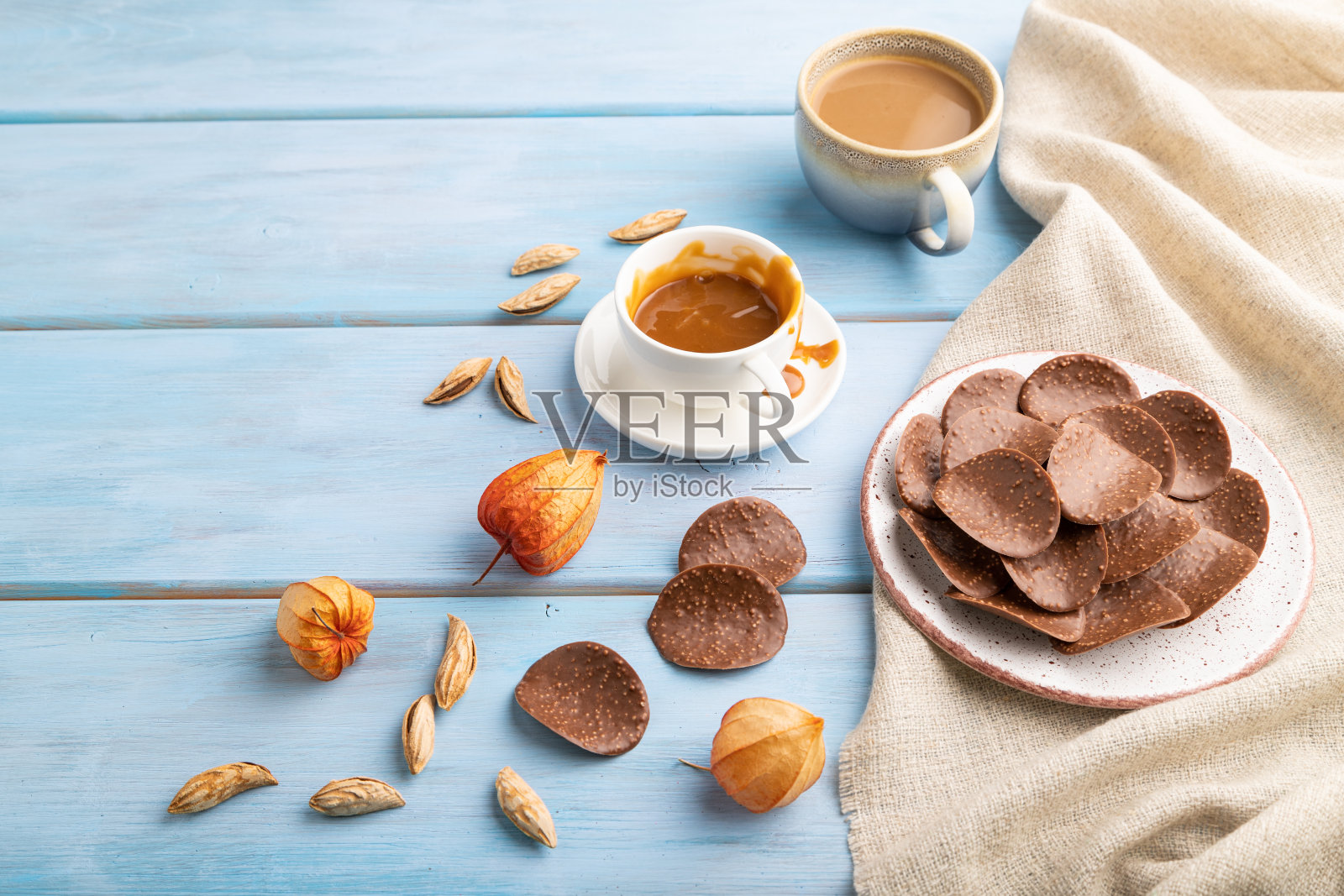 蓝色木质背景上是一杯咖啡和焦糖巧克力片。侧视图，拷贝空间。照片摄影图片