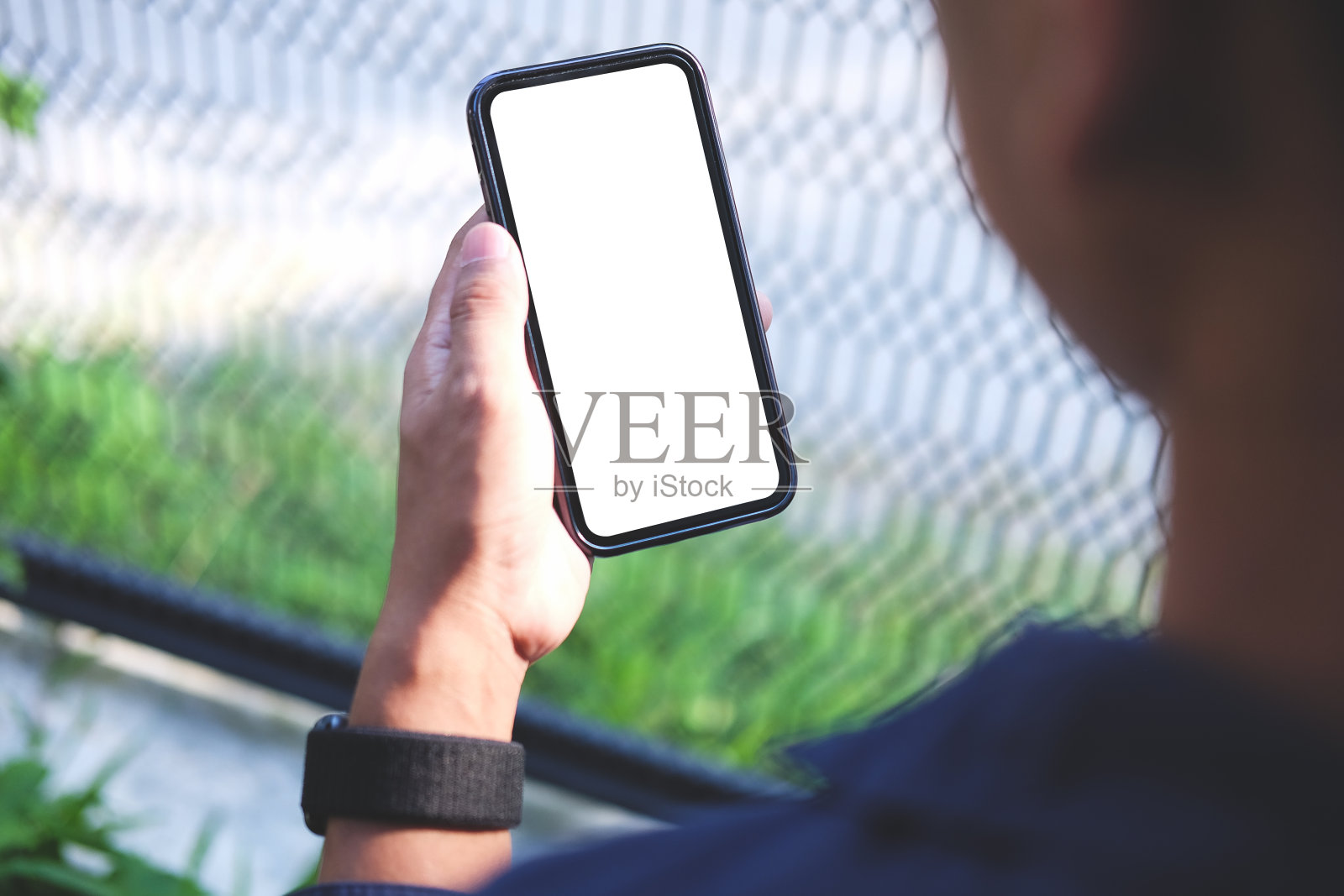 近距离观察年轻人坐在后院使用智能手机。照片摄影图片