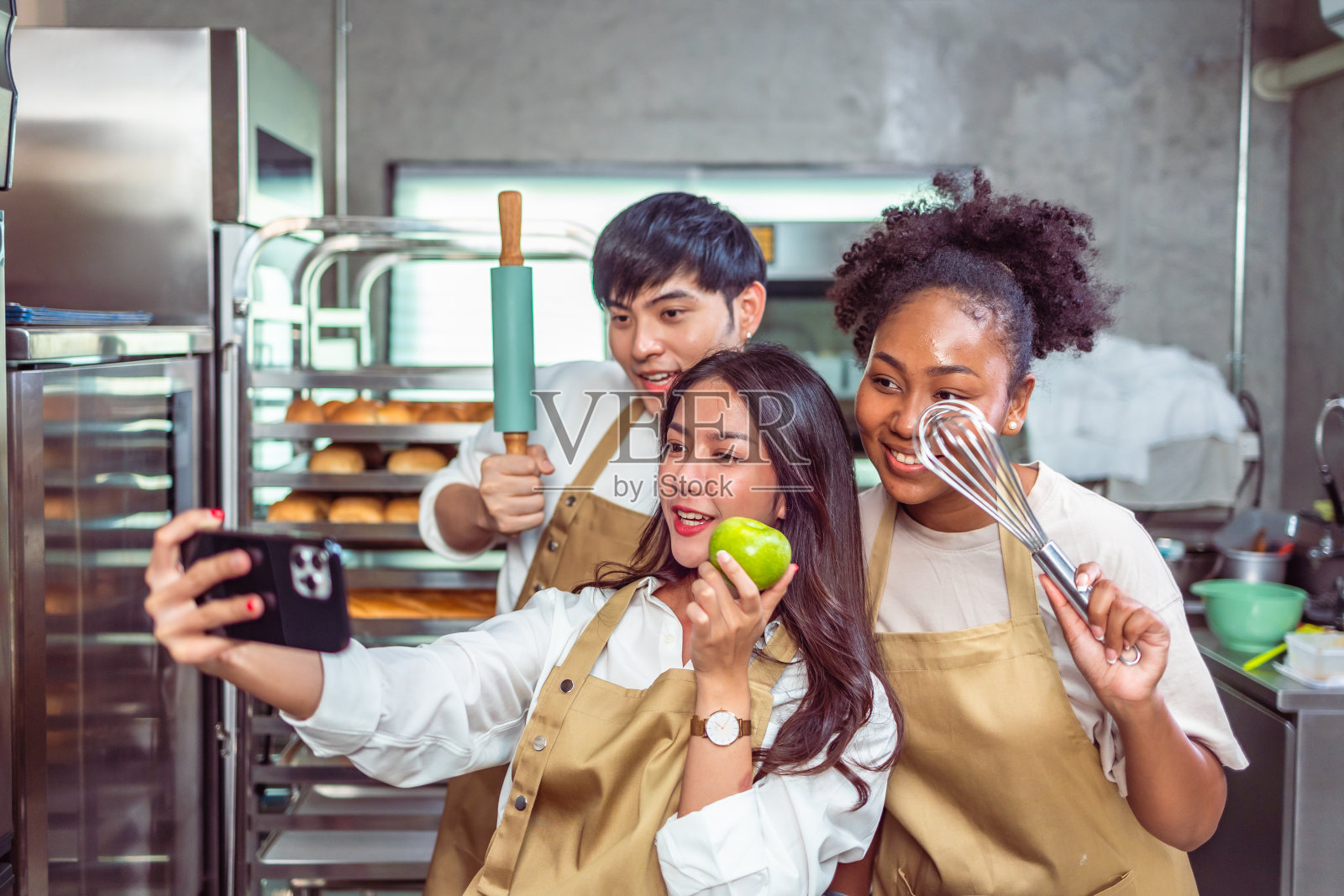 烹饪课的学生在厨房里为食谱混合配料。一群年轻人在烹饪课上自拍。照片摄影图片