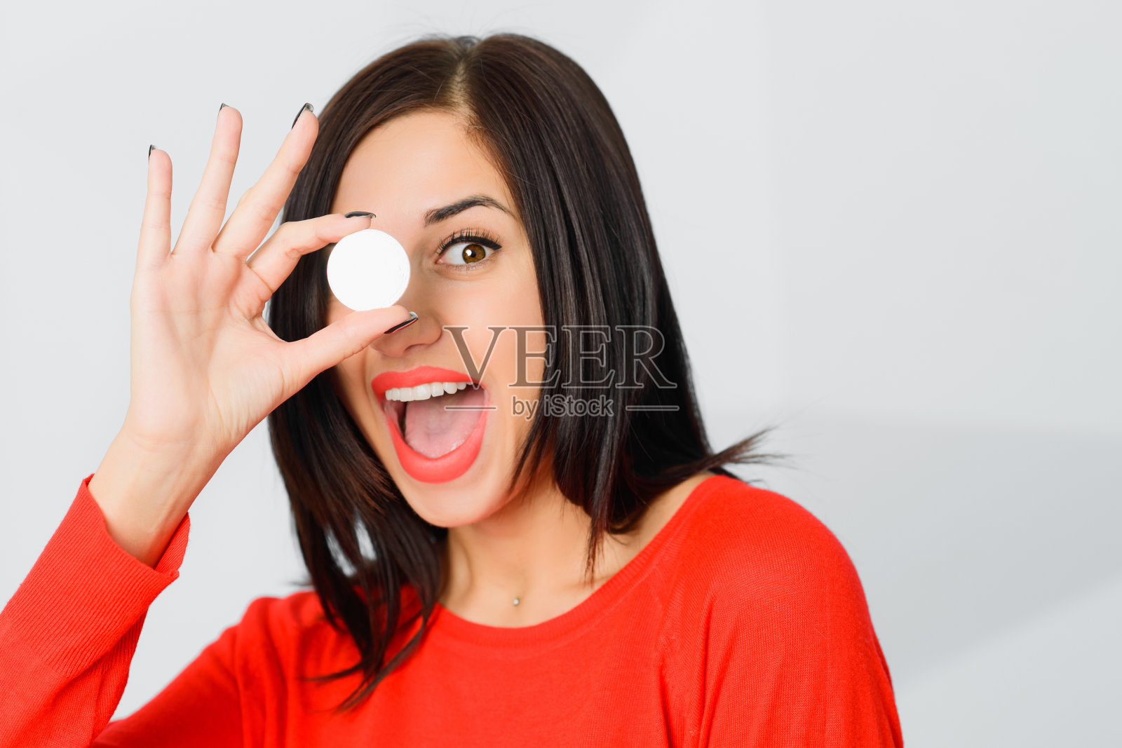 女孩拿着比特币像单片眼镜与OK戒指的手势照片摄影图片