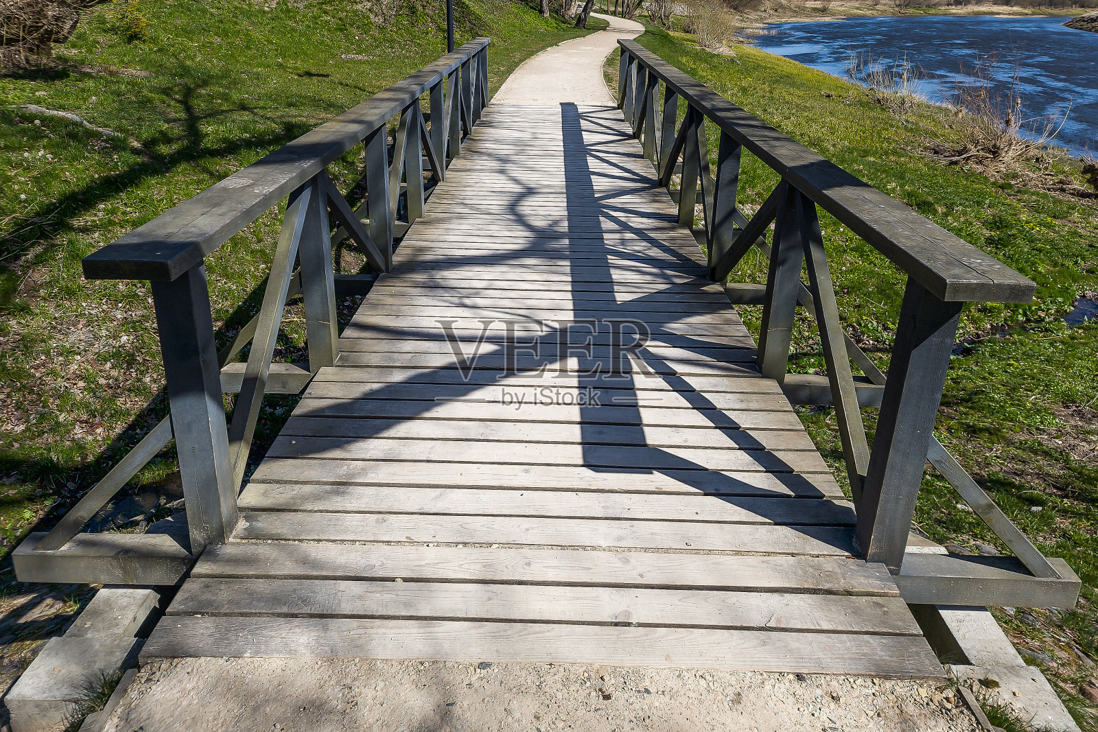 在一个阳光明媚的春日，一条小河上的木桥。在一个阳光明媚的春日，一条小河上的木桥。照片摄影图片
