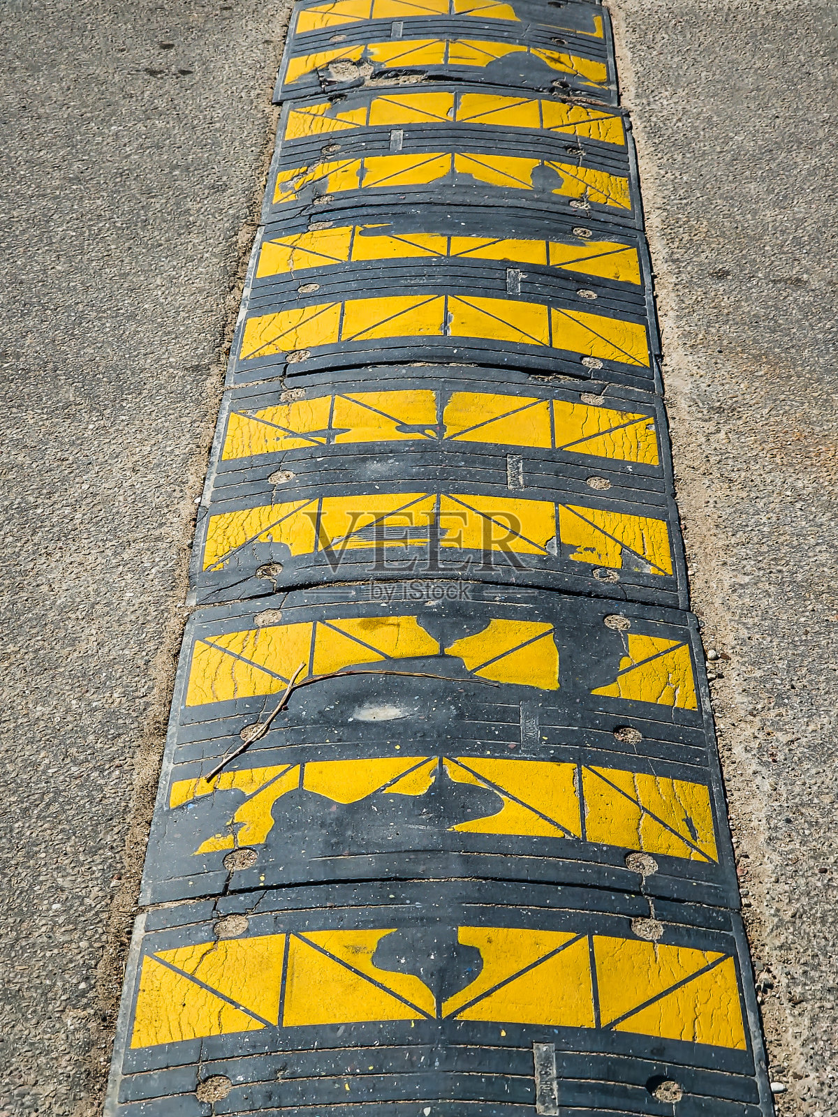 在道路上使用带有黄色条纹的黑色减速带，以降低汽车的速度，防止道路上发生事故。照片摄影图片