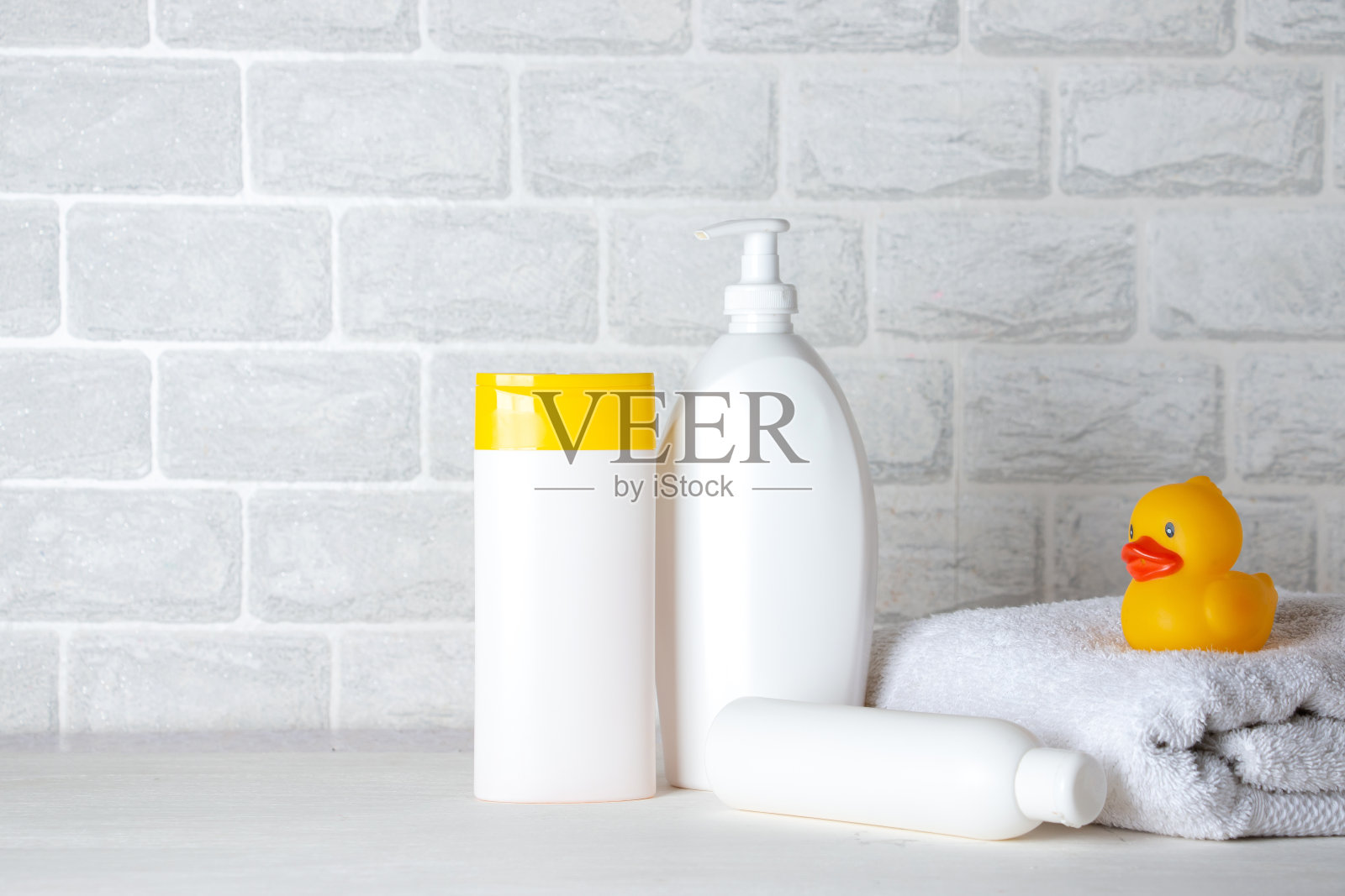 婴儿沐浴用品，毛巾，黄色橡皮鸭和洗发水瓶。儿童保育的概念。照片摄影图片