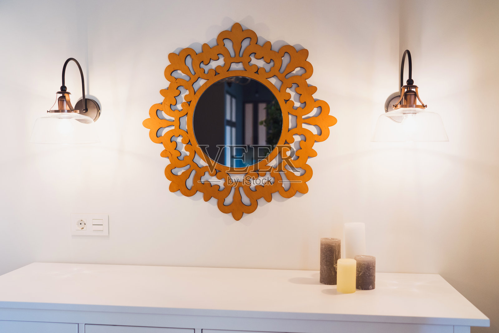 抽屉柜，上面有蜡烛，镜子和对称的灯。照片摄影图片