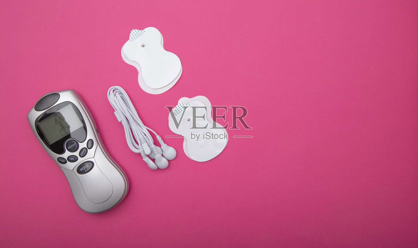 现代医学中的医用电针按摩器。治疗身体疼痛和脂肪燃烧，粉红色背景。为文本复制空间照片摄影图片