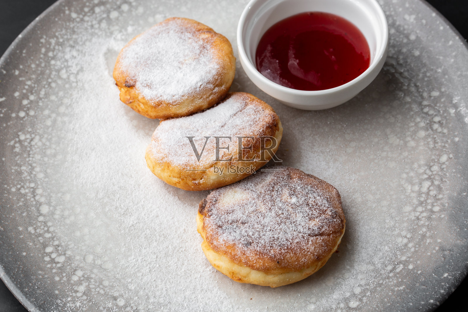 白干酪煎饼，Syrniki或奶酪蛋糕与红酱孤立在黑色大理石背景。自制的食物。美味的早餐。有选择性的重点照片摄影图片