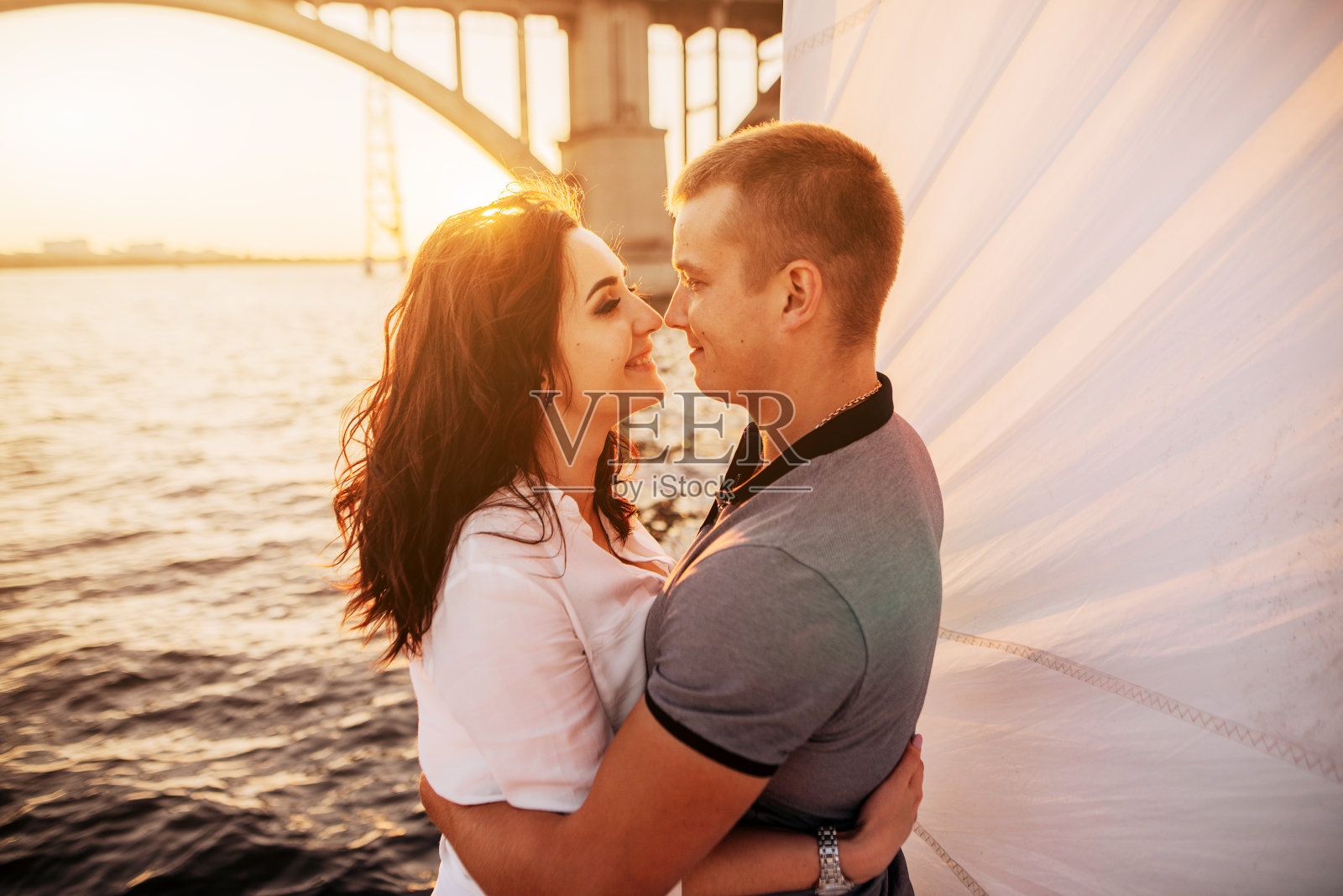 美丽的夫妇在游艇上看着彼此的日落。浪漫的假期照片摄影图片