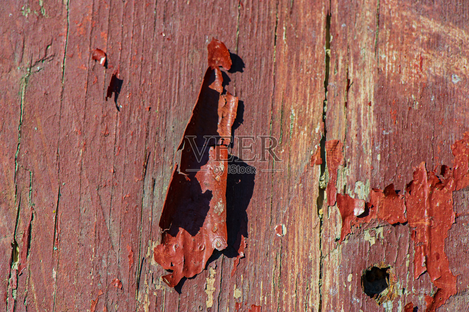 木头表面的红色旧油漆剥落。照片摄影图片