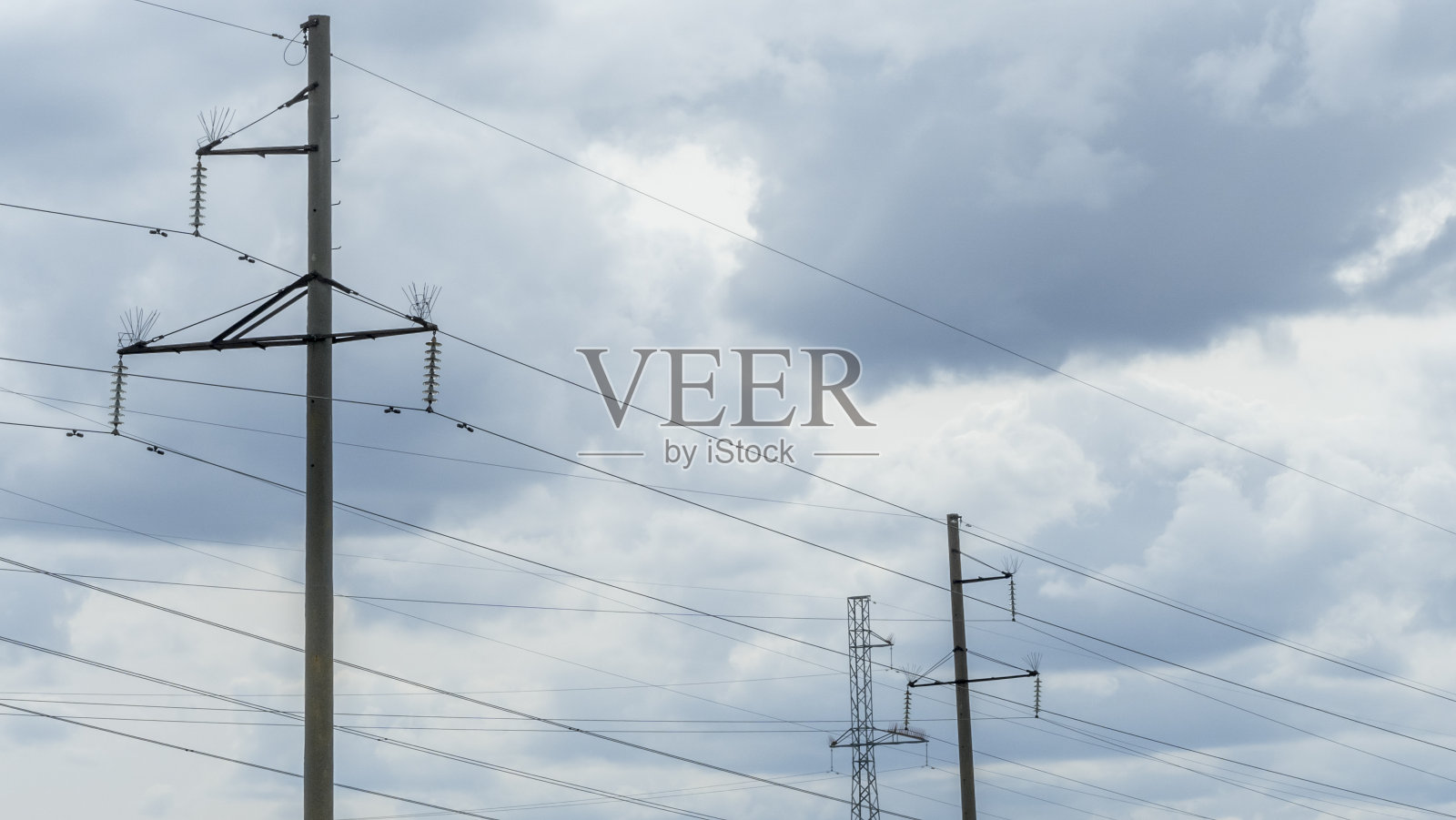 在蓝天白云背景下的高压岗位。蓝天春草上电线杆网。照片摄影图片