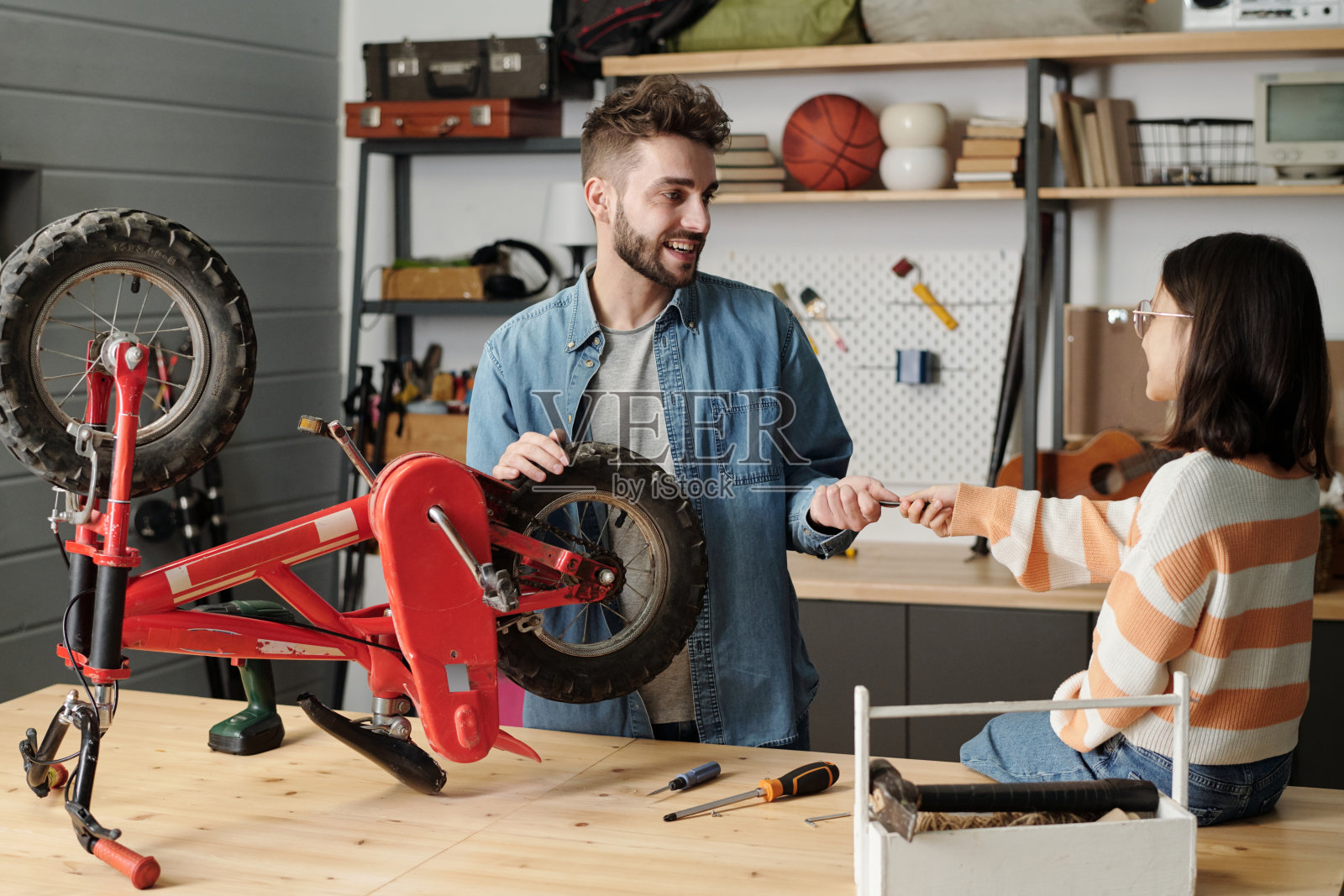 快乐的年轻人接过女儿在车库里递给他的手动工具照片摄影图片