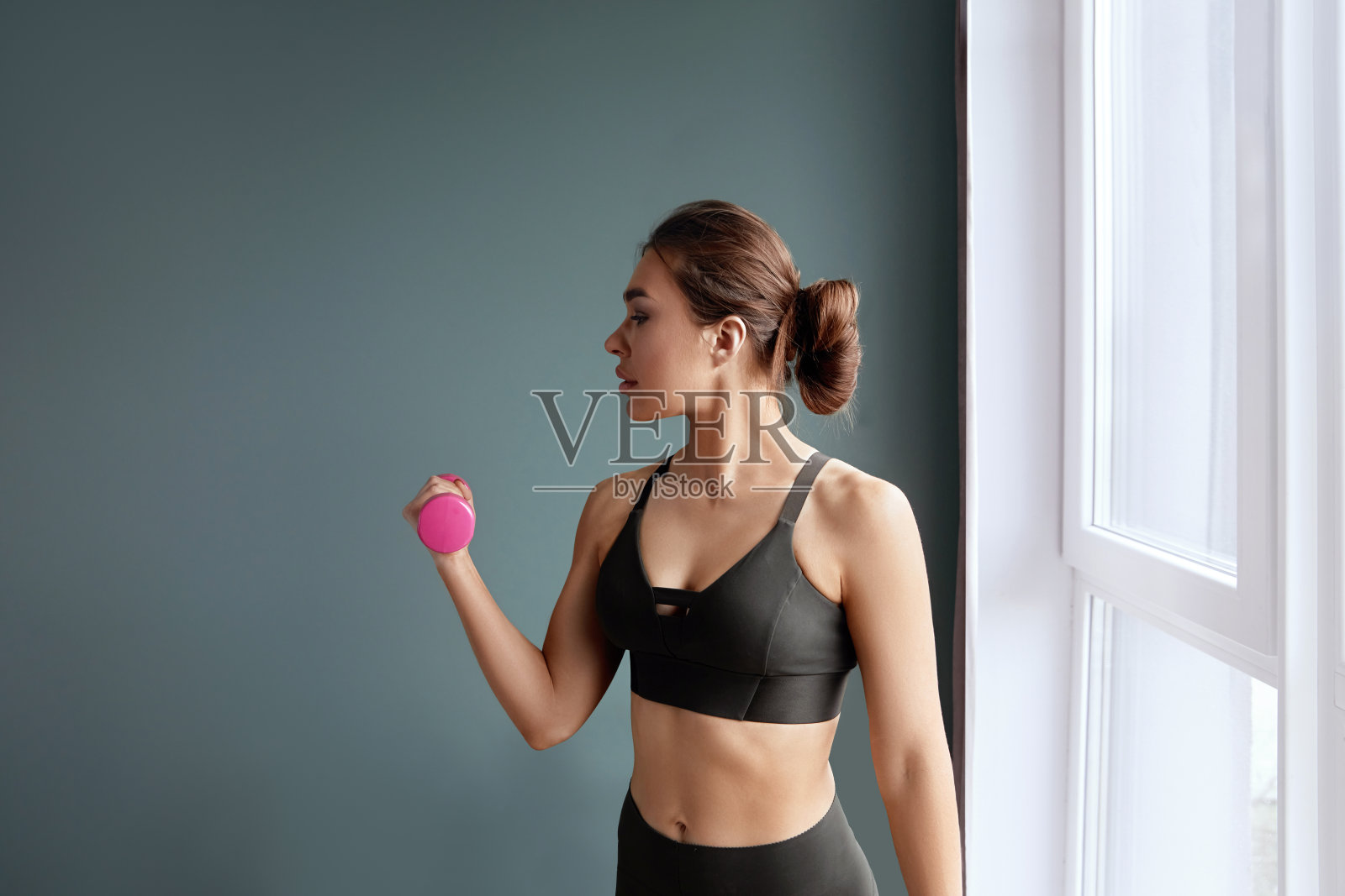 年轻女子做哑铃锻炼，锻炼手臂力量，看看复印空间。微笑的运动女士举哑铃。照片摄影图片