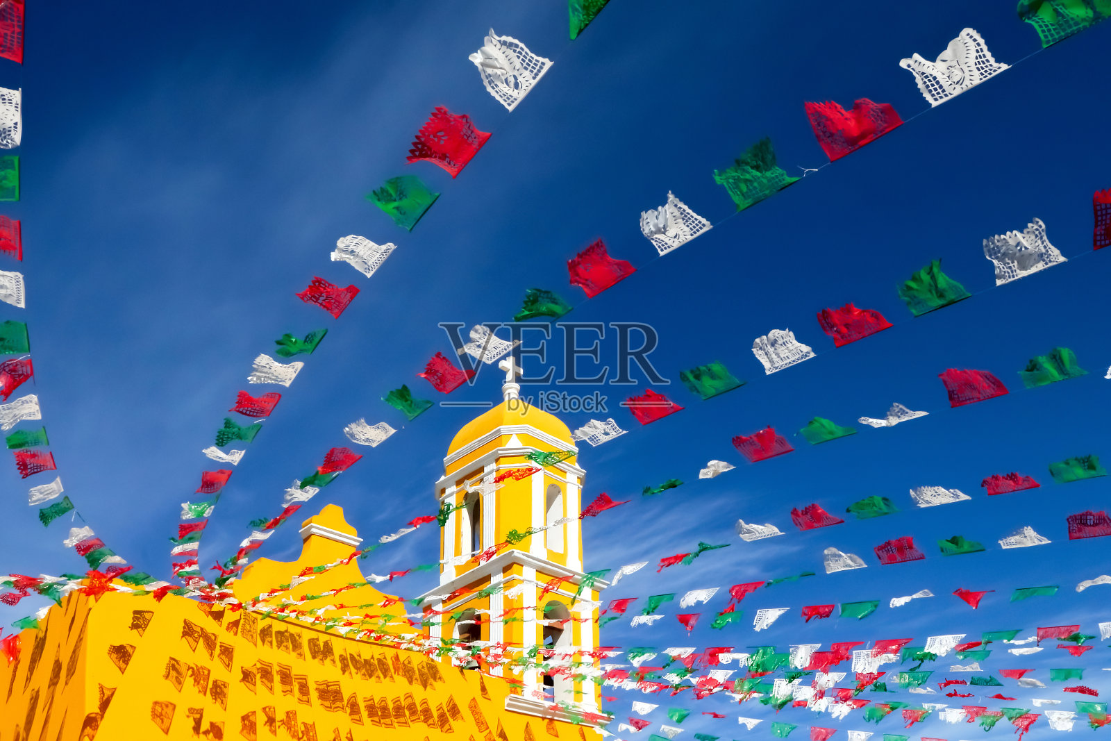 黄色的天主教堂和节日旗帜映衬着蓝天。墨西哥。伊扎迈勒老城。照片摄影图片