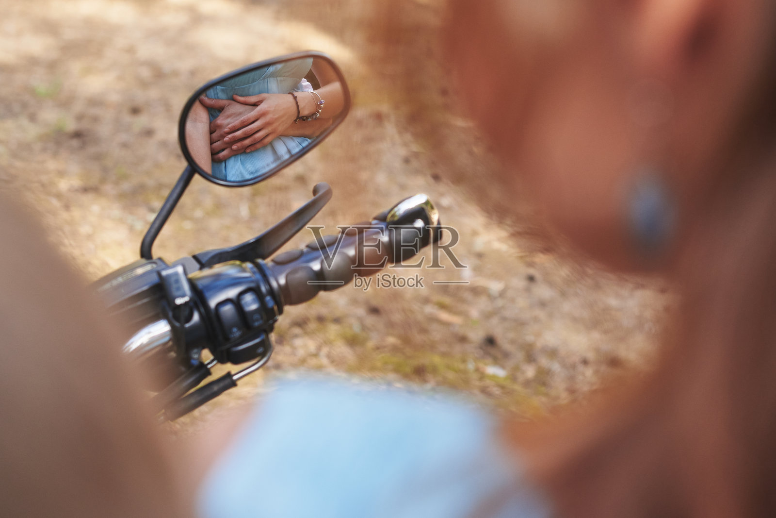 摩托车的镜子里映出一个女人的手放在一个男人的手上，搂着女人的腰照片摄影图片