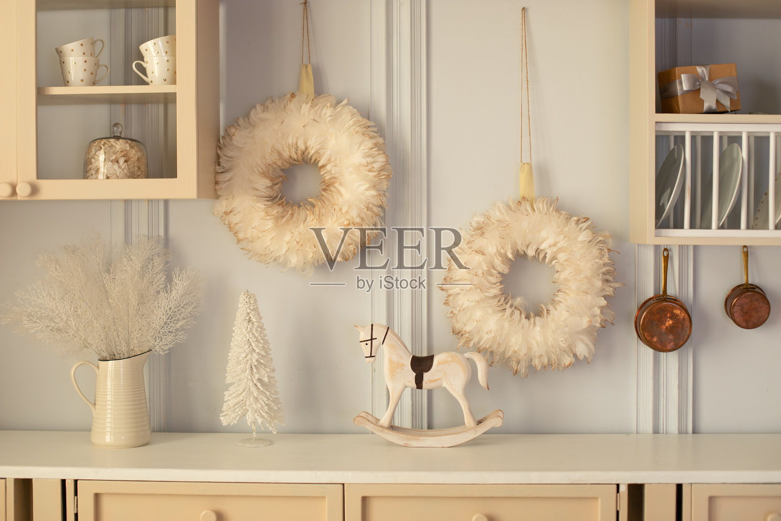 烹饪与舒适的家庭装饰。厨房内部有木制橱柜和装饰，器皿，锅和盘子。厨房桌面上的炊具和陶瓷盘子。圣诞节，小雕像摇马照片摄影图片