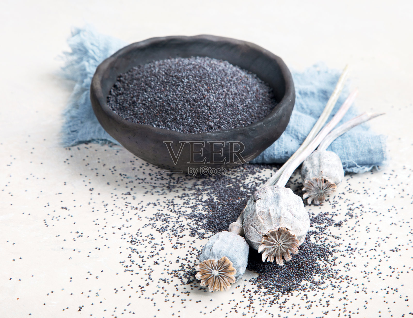 在灰色背景上与罂粟种子组合。照片摄影图片