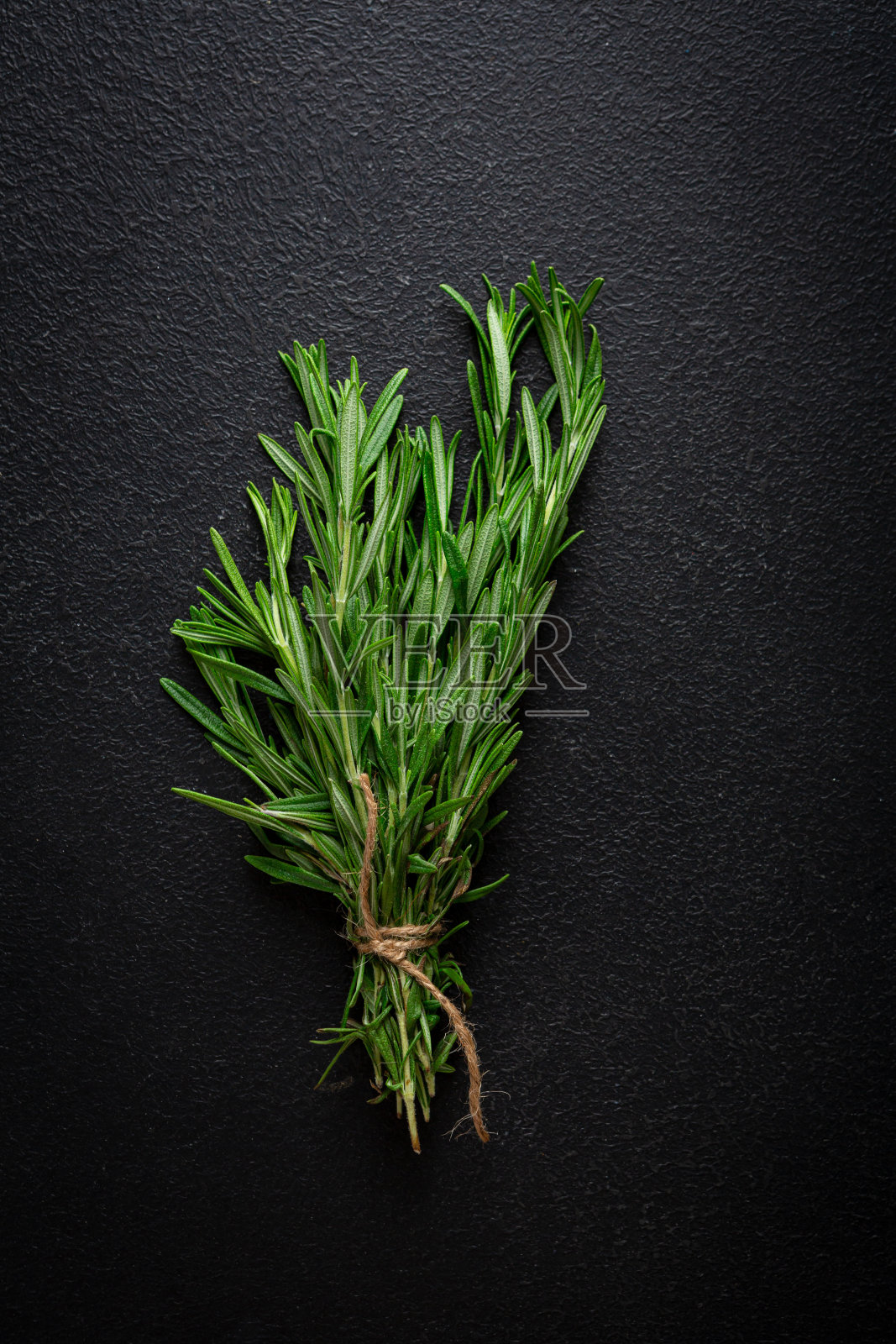 黑色表面撒上一串绿色有机迷迭香香料照片摄影图片