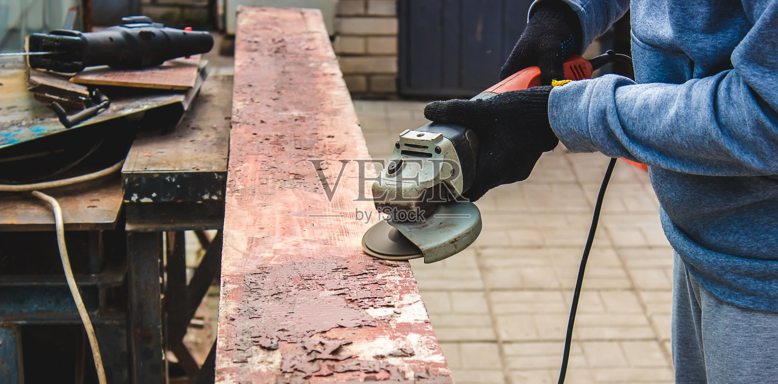 一个男人正在磨一块木板。清除木板上的旧漆。木工工作。照片摄影图片