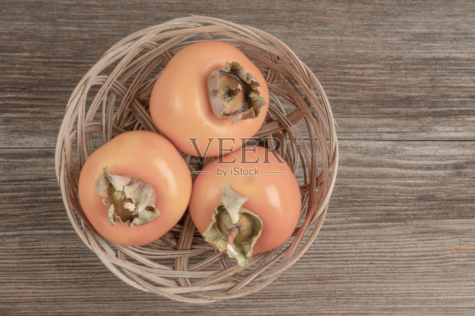 熟柿子放在木桌上的篮子里照片摄影图片