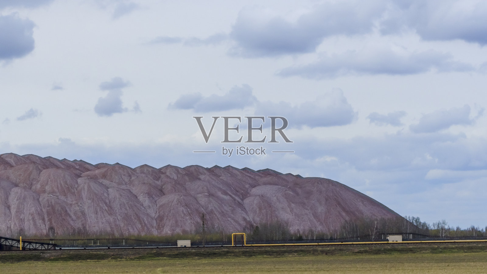 在多云的天空背景下开采钾矿时的空矿山。把一块空石头运到垃圾场。照片摄影图片