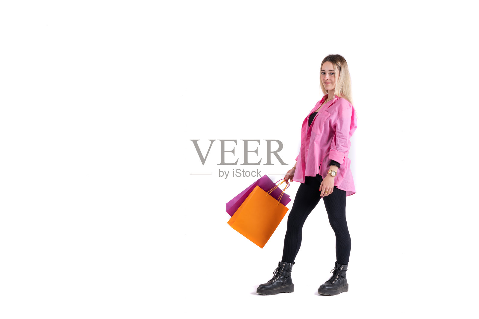 年轻女子站着摆姿势，手里拿着购物袋看着相机照片摄影图片