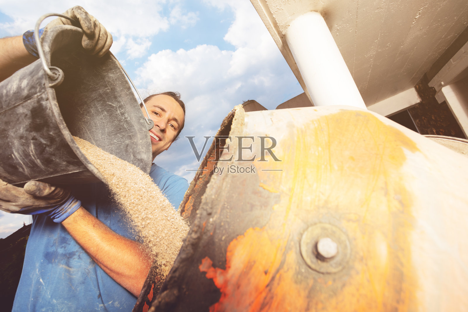 男子将一桶沙子倒入水泥搅拌机特写镜头照片摄影图片