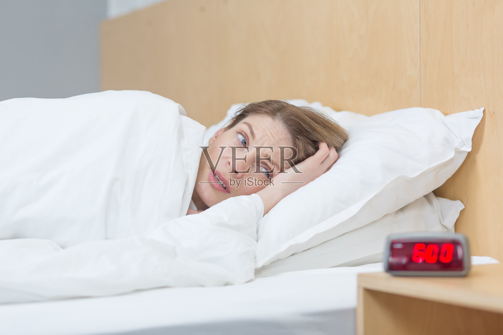 这位女士早上醒来，沮丧地看着闹钟照片摄影图片