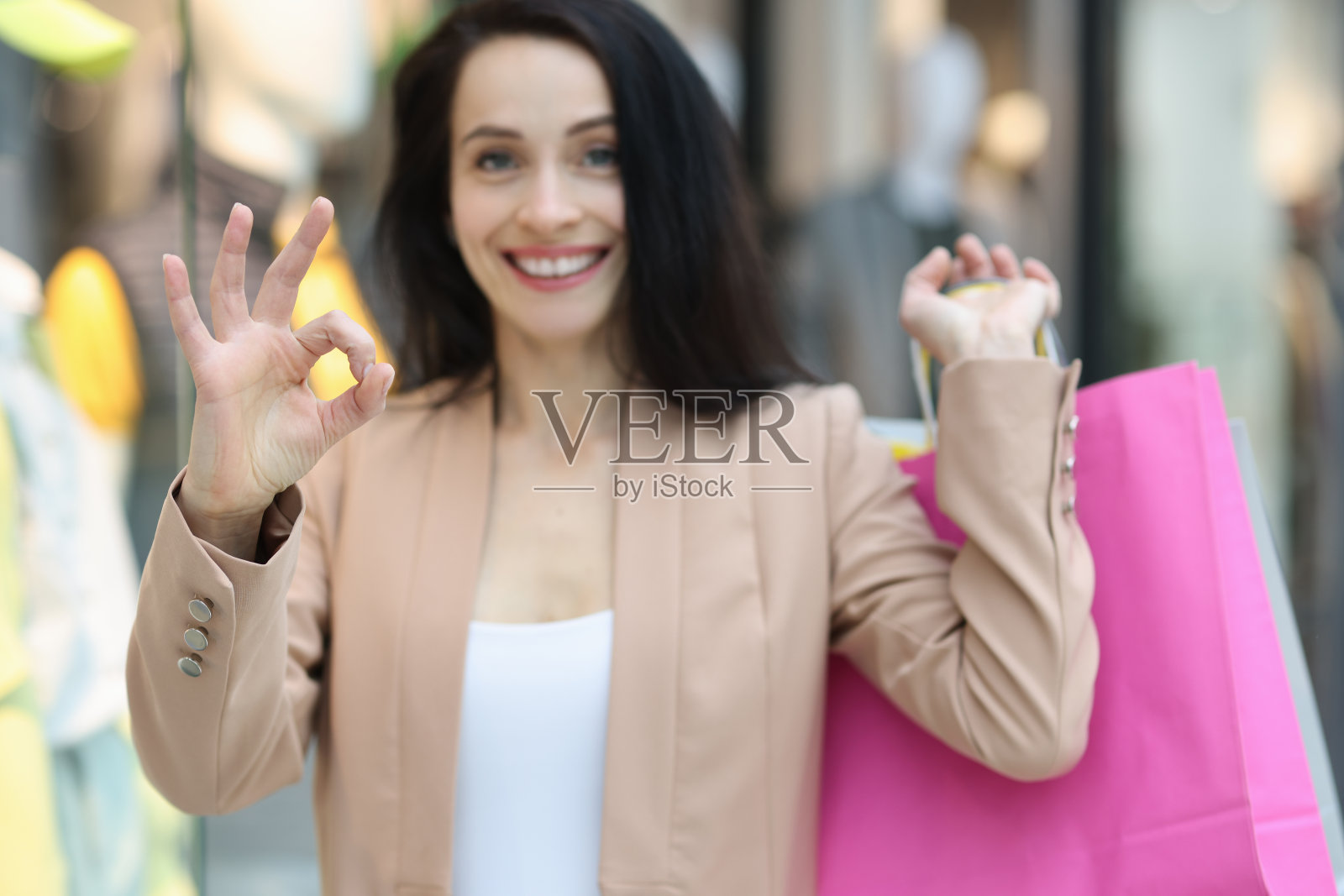 快乐微笑的女人，带着购物袋，摆出ok的姿势照片摄影图片