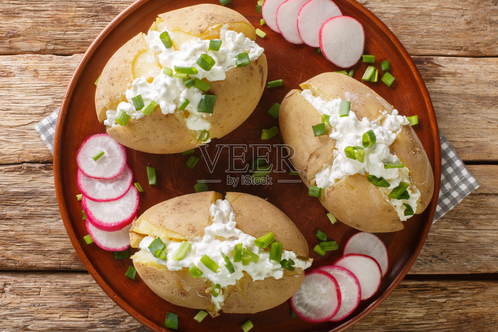 自制土豆填满了腌白软干酪，酸奶油和大葱，放在盘子里。水平的俯视图照片摄影图片