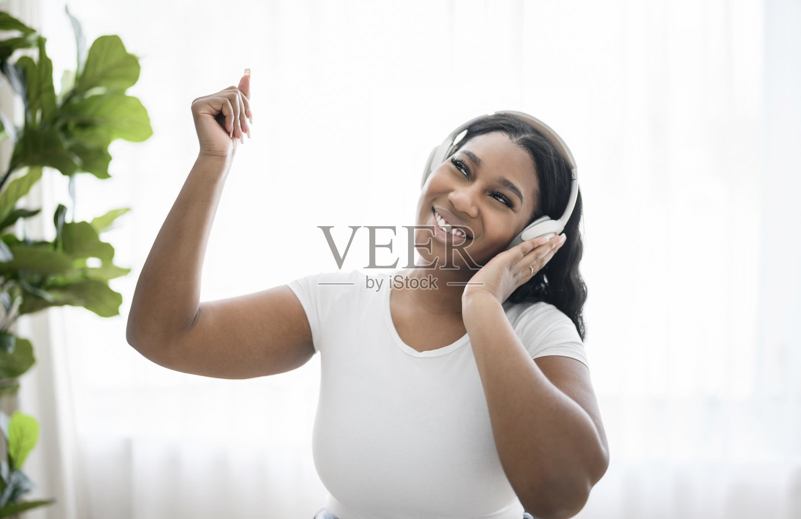迷人的年轻非洲女人听音乐与耳机在家里照片摄影图片