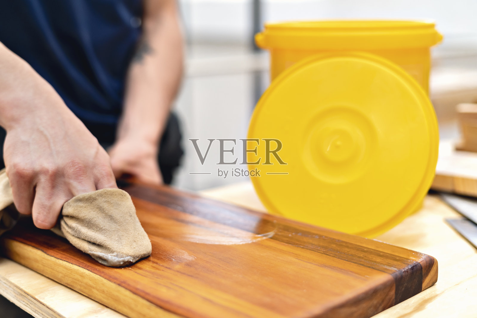 木匠用抹布打磨一块木头。照片摄影图片