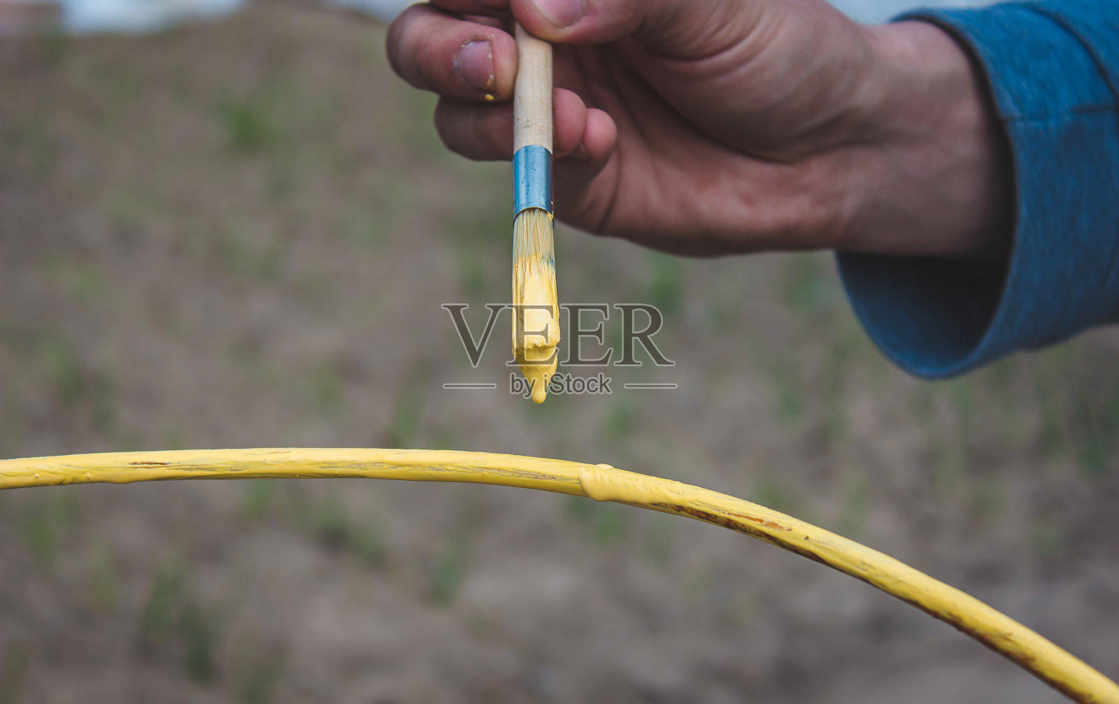 一个男人用黄色和蓝色的颜料画一个铁框架。照片摄影图片