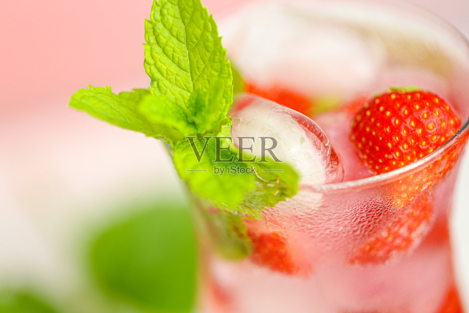 草莓酒。夏季饮料。清爽鸡尾酒。一杯矿泉水加冰和草莓。矿泉水加冰和草莓在一个玻璃杯和成熟的草莓叶子。照片摄影图片