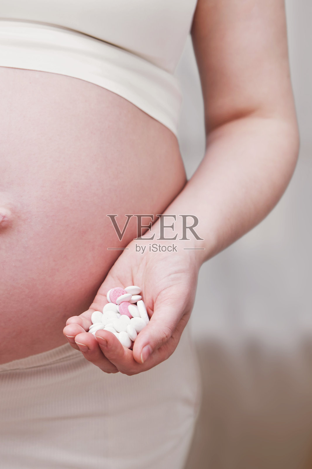 肚子上有药片的孕妇，家里的客厅照片摄影图片