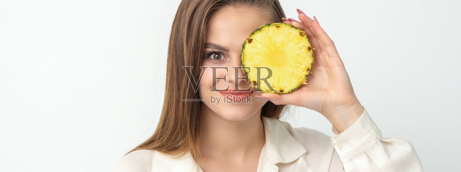 有吸引力的漂亮漂亮的年轻白人妇女持有切片菠萝覆盖她的眼睛孤立的白色背景。照片摄影图片