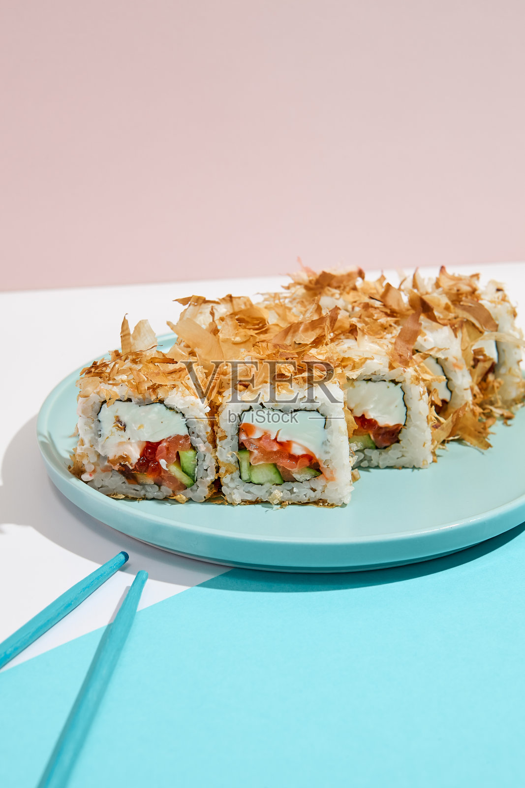 现代彩色背景上的金枪鱼寿司卷，内含三文鱼、奶酪、黄瓜，外裹金枪鱼。简约风格的鲣鱼寿司卷，日式菜单概念。照片摄影图片