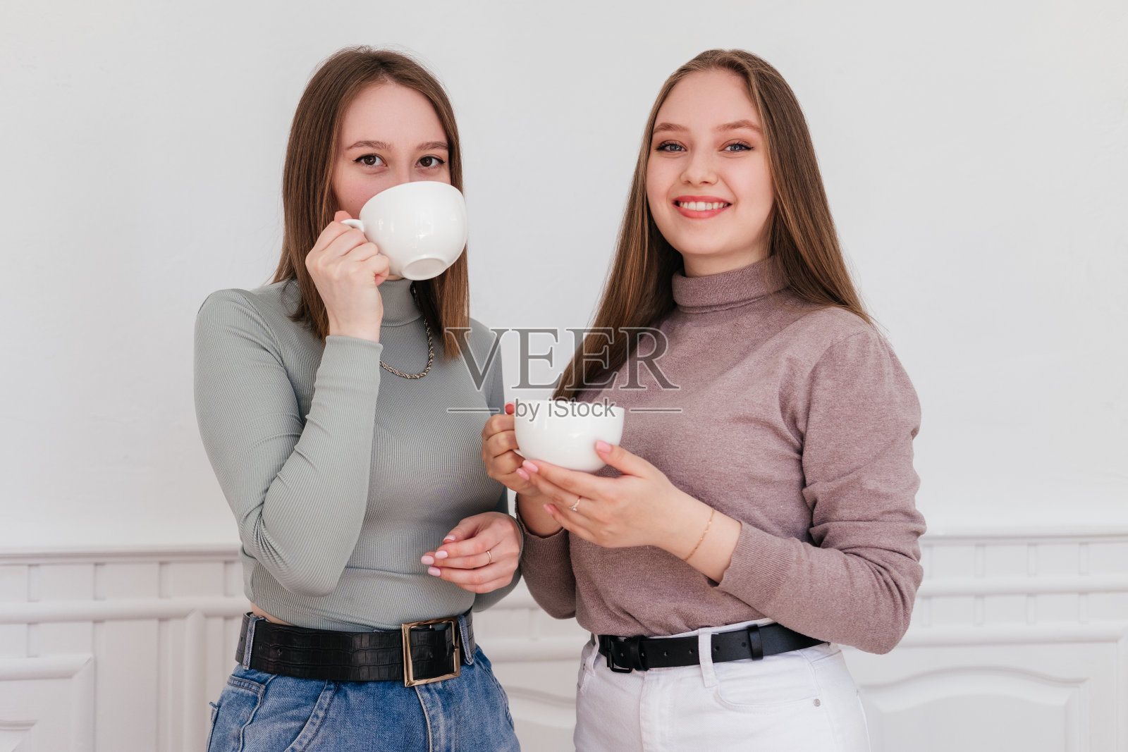 两个笑着的年轻女性朋友在咖啡馆喝咖啡。在室内的女孩聊天照片摄影图片