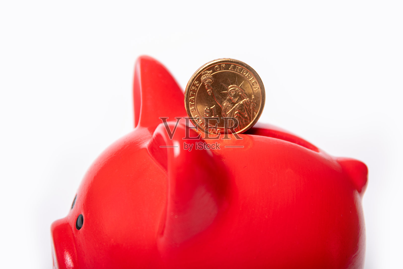 在白色背景的红色储蓄罐的洞里投1美元。储蓄的概念。国家货币的稳定照片摄影图片