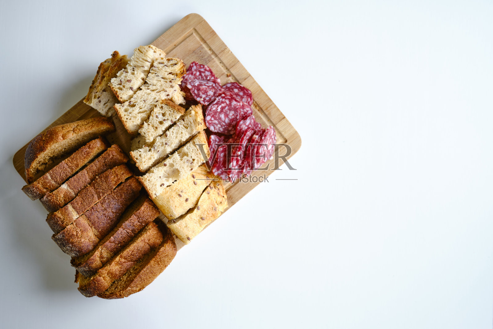 开胃菜配切片面包和香肠。开胃菜的酒。美味的小吃在一个明亮的背景，在木板上照片摄影图片