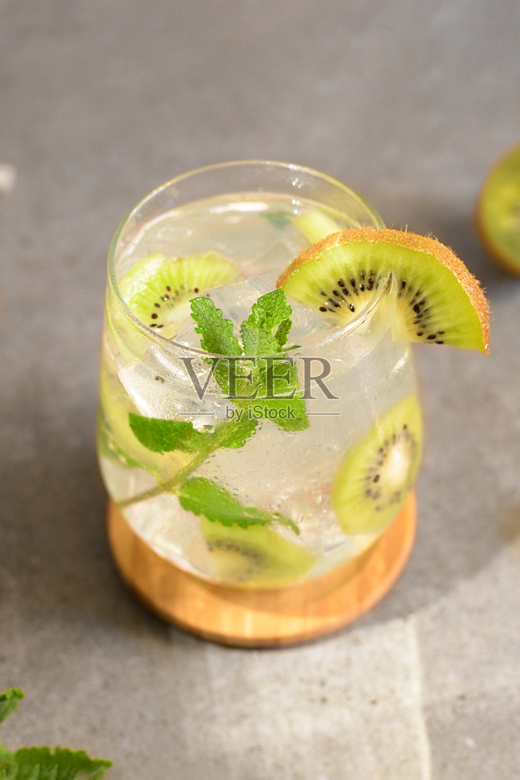 猕猴桃莫吉托鸡尾酒或凯匹林纳饮料食谱与薄荷和冰在玻璃杯中接近。夏天冷饮猕猴桃柠檬水照片摄影图片