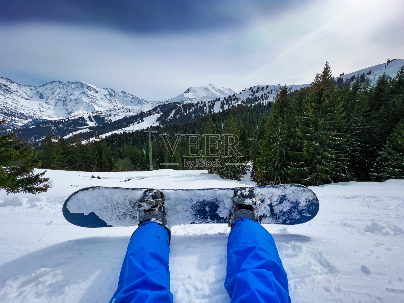 坐在滑雪缆车上的男子，腿固定在滑雪板上照片摄影图片