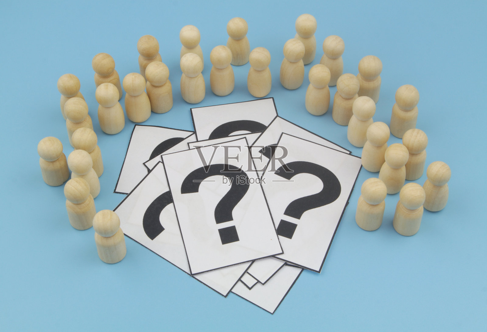 木制的人围绕着蓝色背景上的问号。照片摄影图片