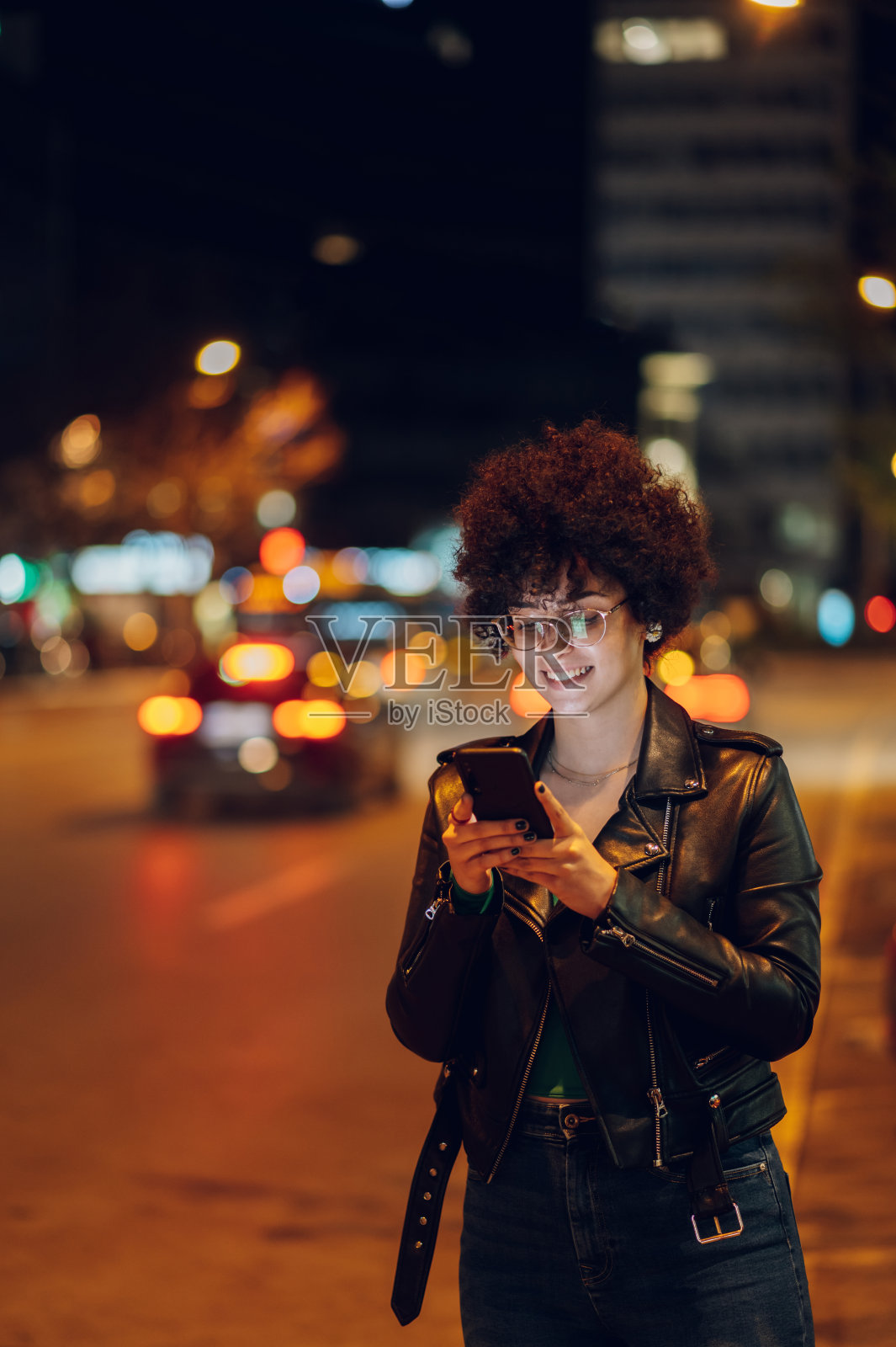 一个留着爆炸头的女人在城外用智能手机照片摄影图片
