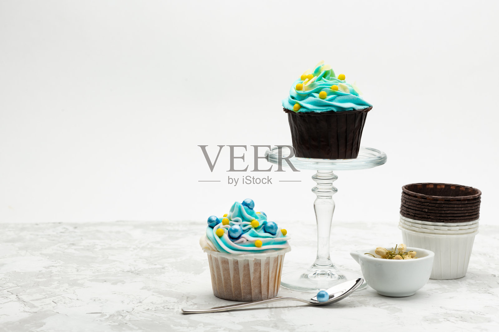 浅灰色的桌子上，五颜六色的小蛋糕装饰着五颜六色的糖果。照片摄影图片