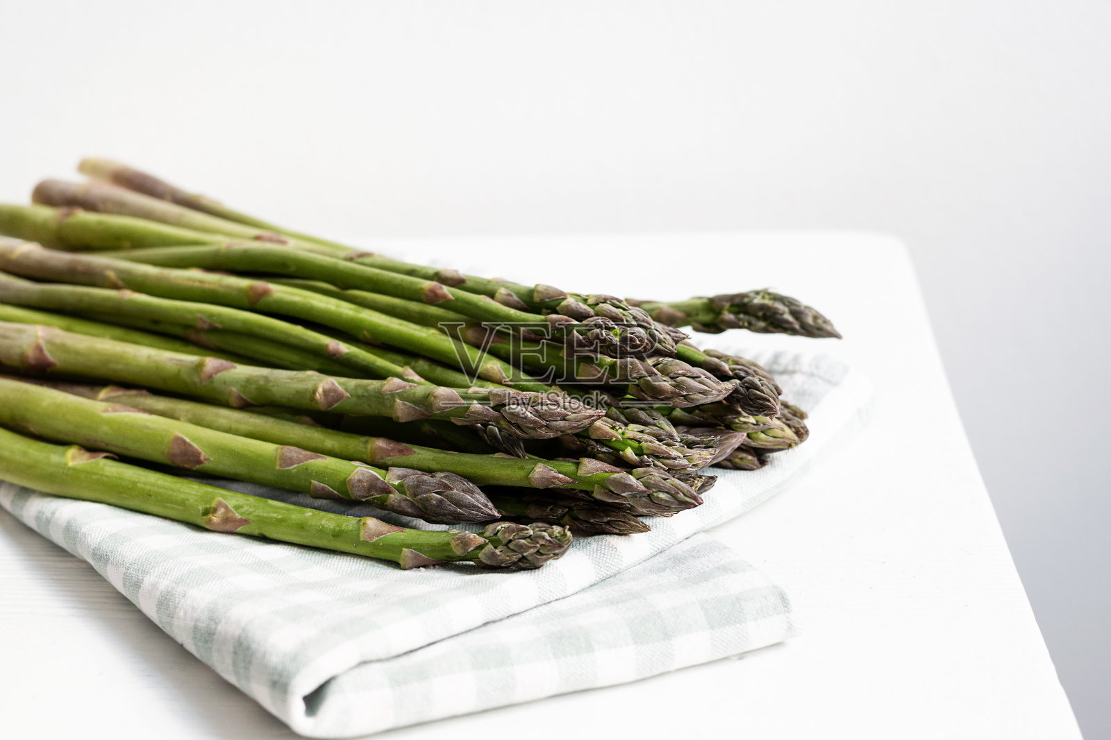 一束绿色芦笋，在白色底色的毛巾上，生蔬菜。照片摄影图片