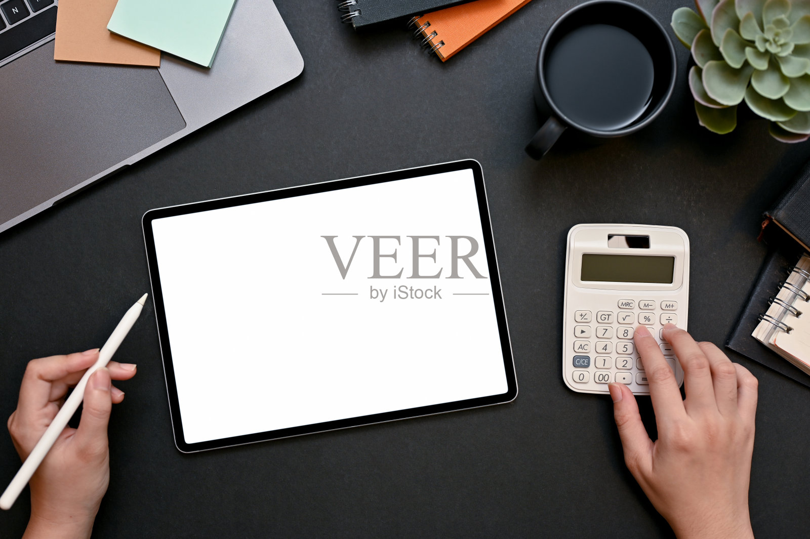 女商人或女金融分析师使用计算器和平板电脑工作。照片摄影图片