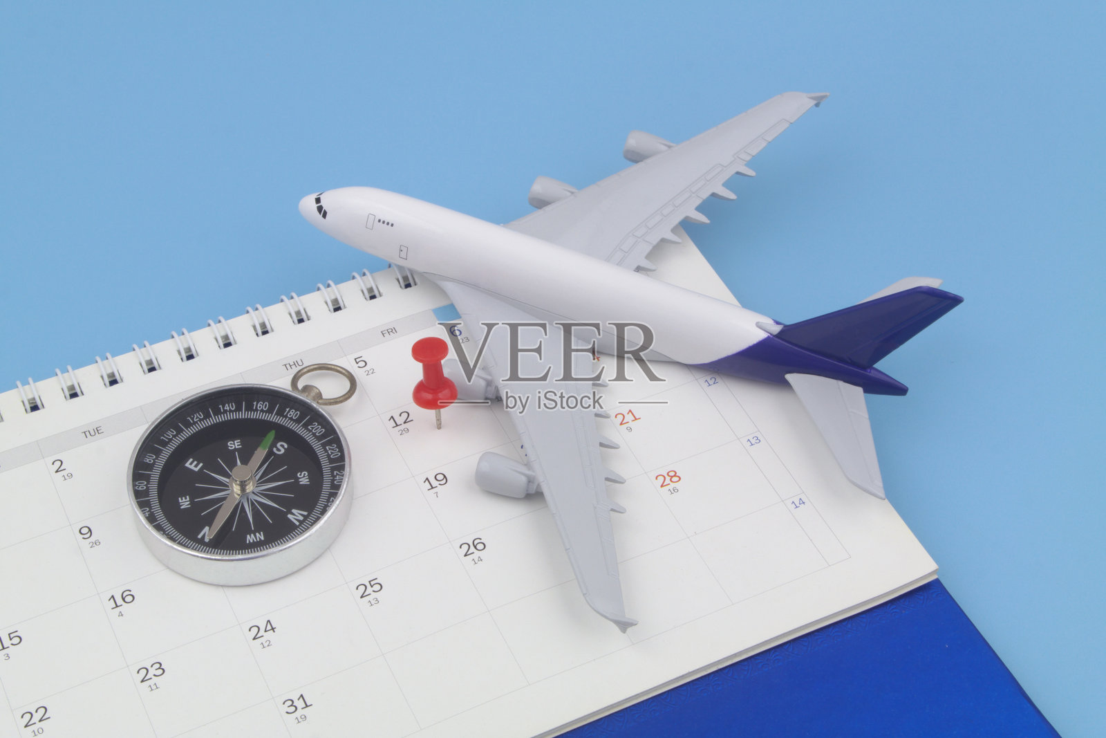 日历页上的飞机模型、黑色指南针和图钉照片摄影图片