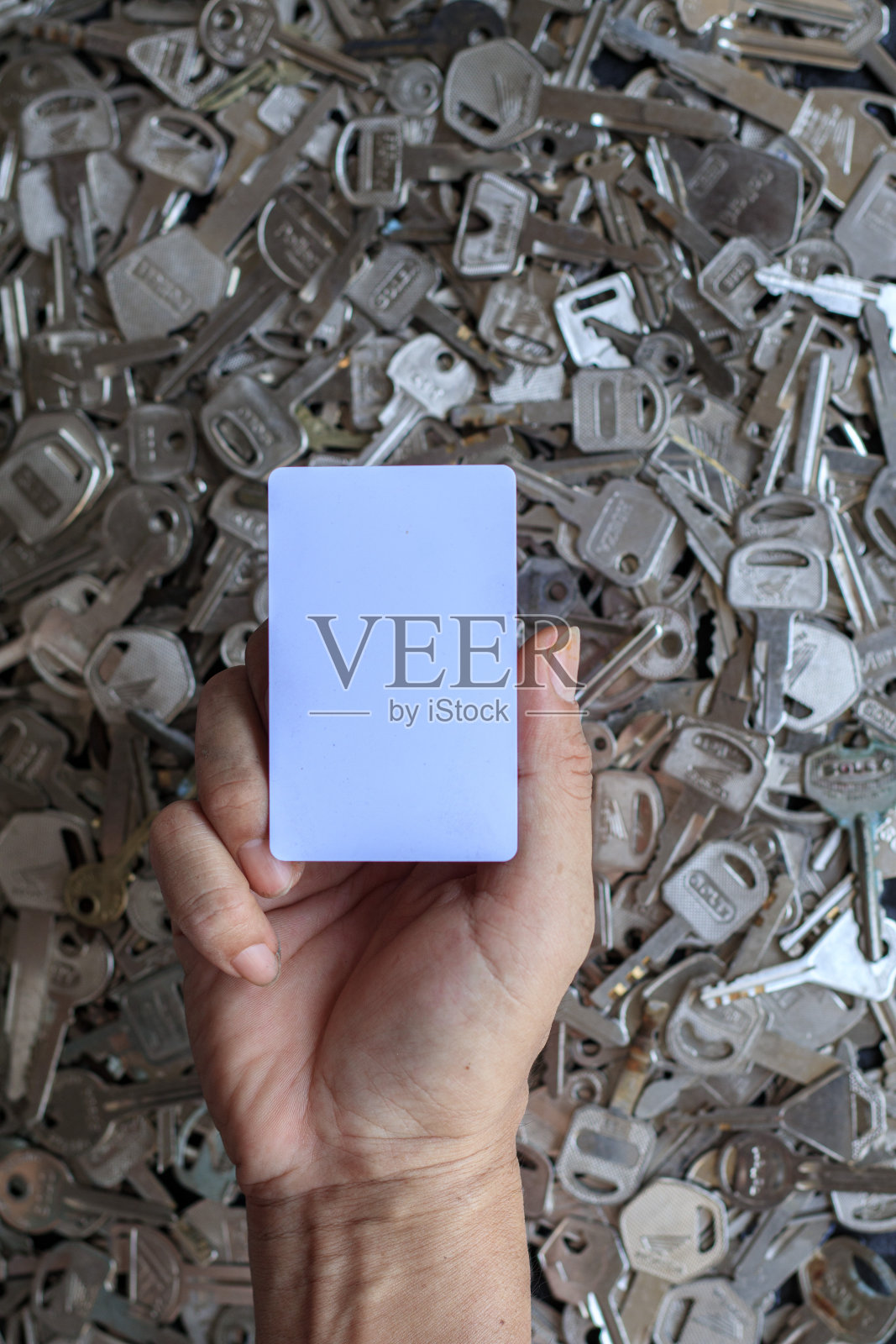 在客户希望携带钥匙卡后，锁匠将备用的白色钥匙卡交给客户，以创建一个新的钥匙卡，以防止许多旧钥匙背景模糊而丢失照片摄影图片