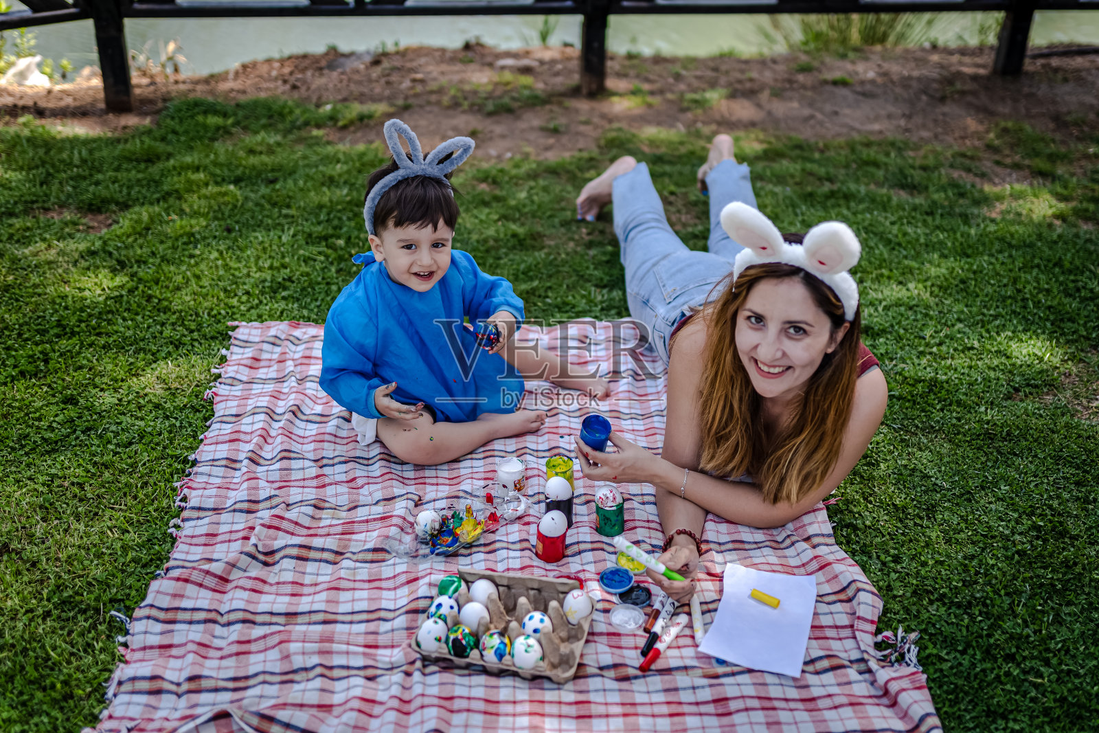 妈妈和她的小男孩在花园里给复活节彩蛋着色照片摄影图片